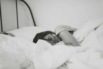 grayscale photo of sleeping woman lying on bed